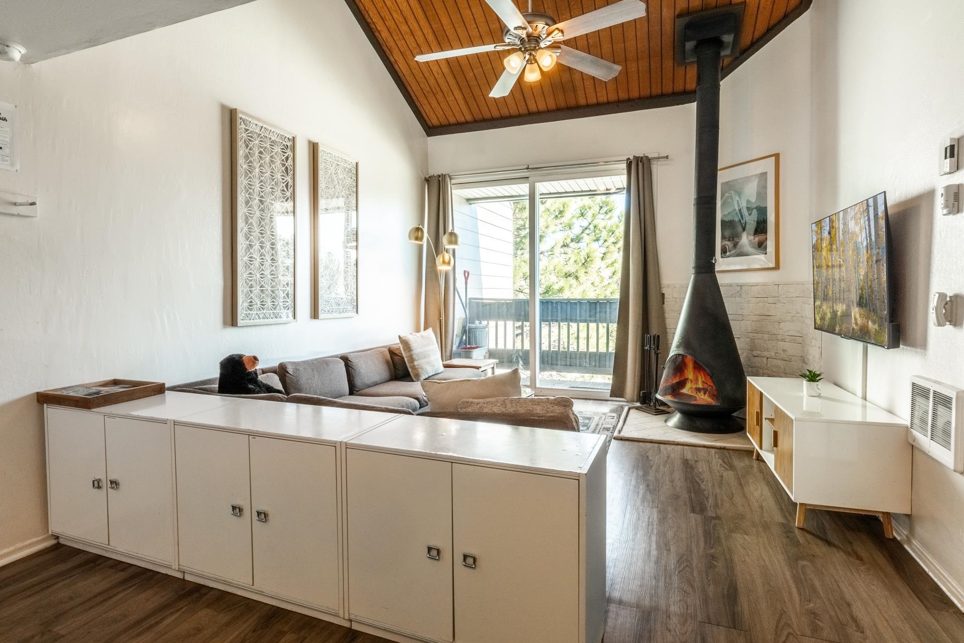 Living area featuring a wood stove, a ceiling fan, a vaulted wood ceiling, dark wood-type flooring, and heating unit