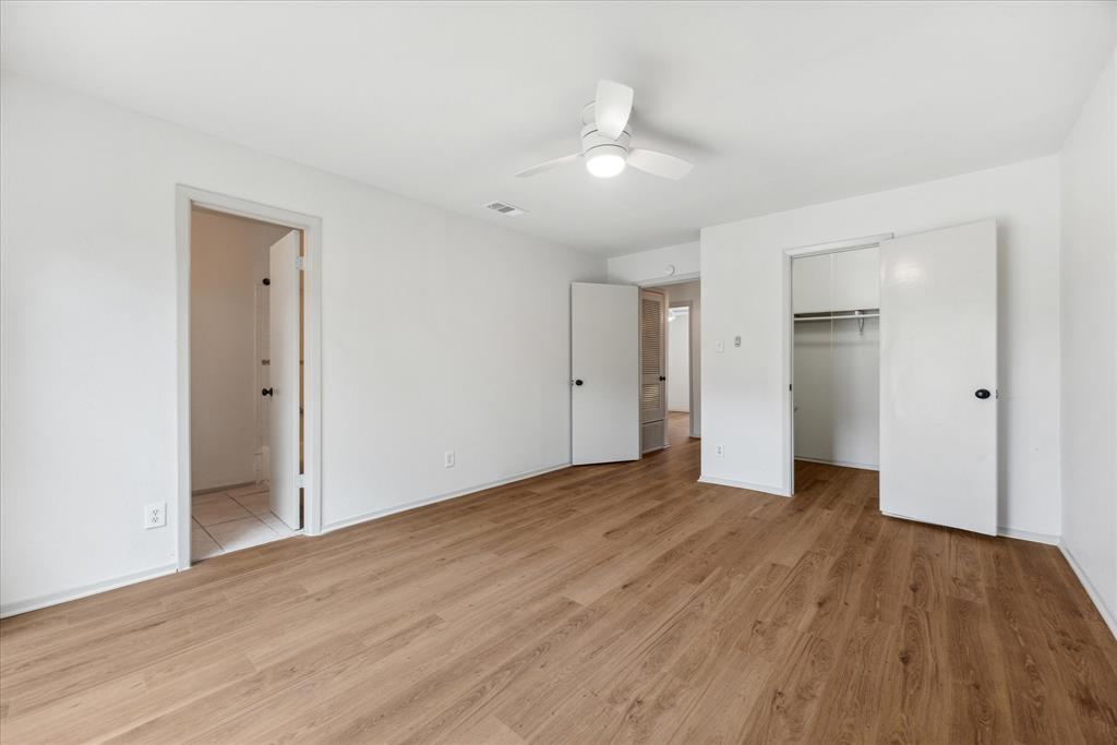 807 Castle Ridge Road, Unit A Austin, TX 78746 - Photo 8 of 15 Unfurnished bedroom featuring light wood-style floors, a walk in closet, ceiling fan, connected bathroom, and a closet
