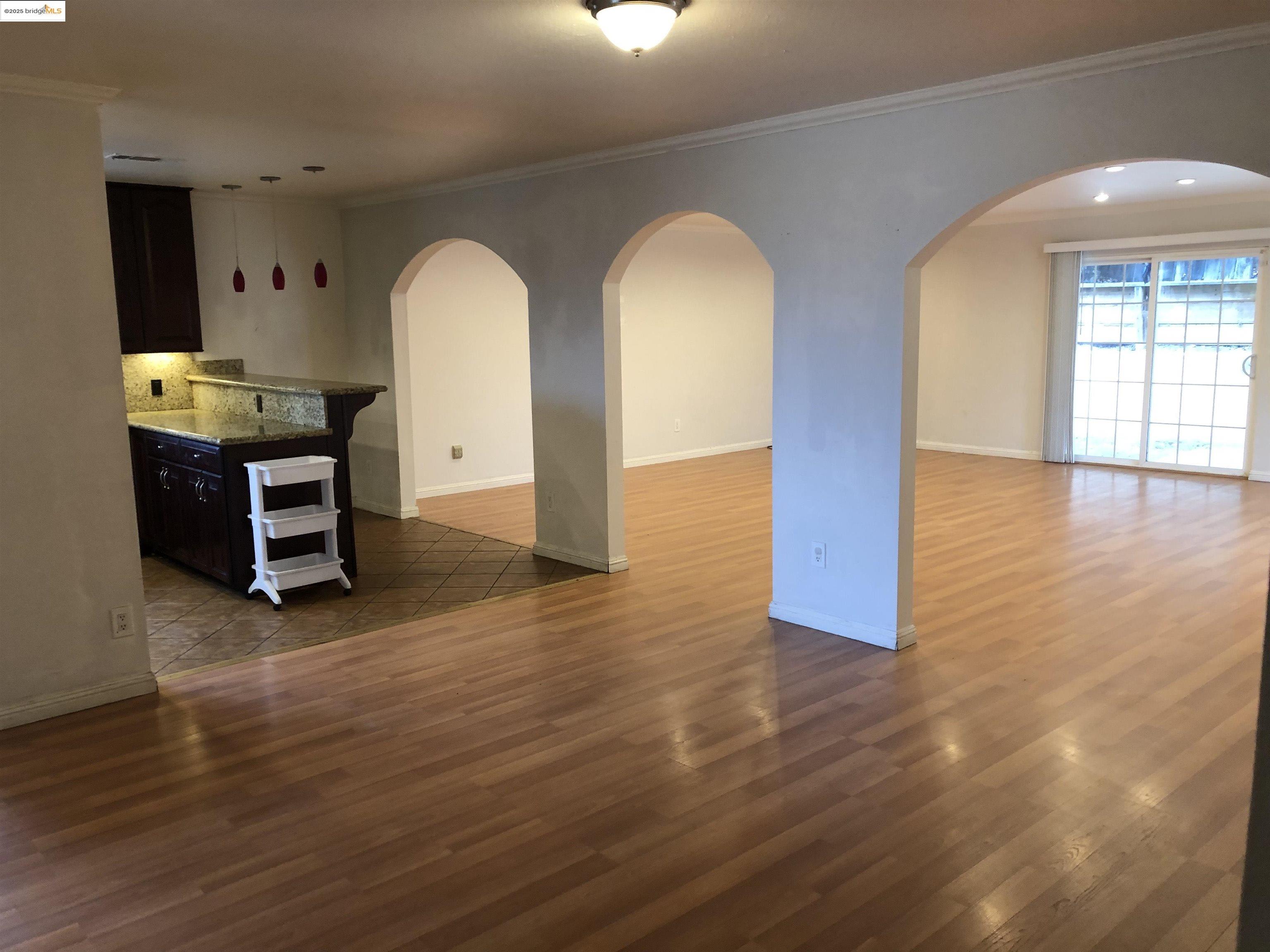 2174 Sugartree Drive Pittsburg, CA 94565 - Photo 11 of 12 Unfurnished living room featuring arched walkways, dark wood-type flooring, and crown molding