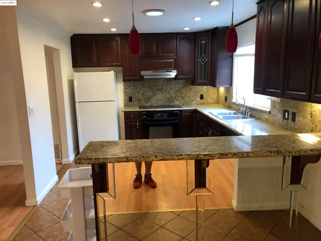 a kitchen with kitchen island granite countertop a sink and refrigerator