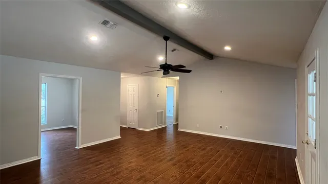 an empty room with wooden floor and windows