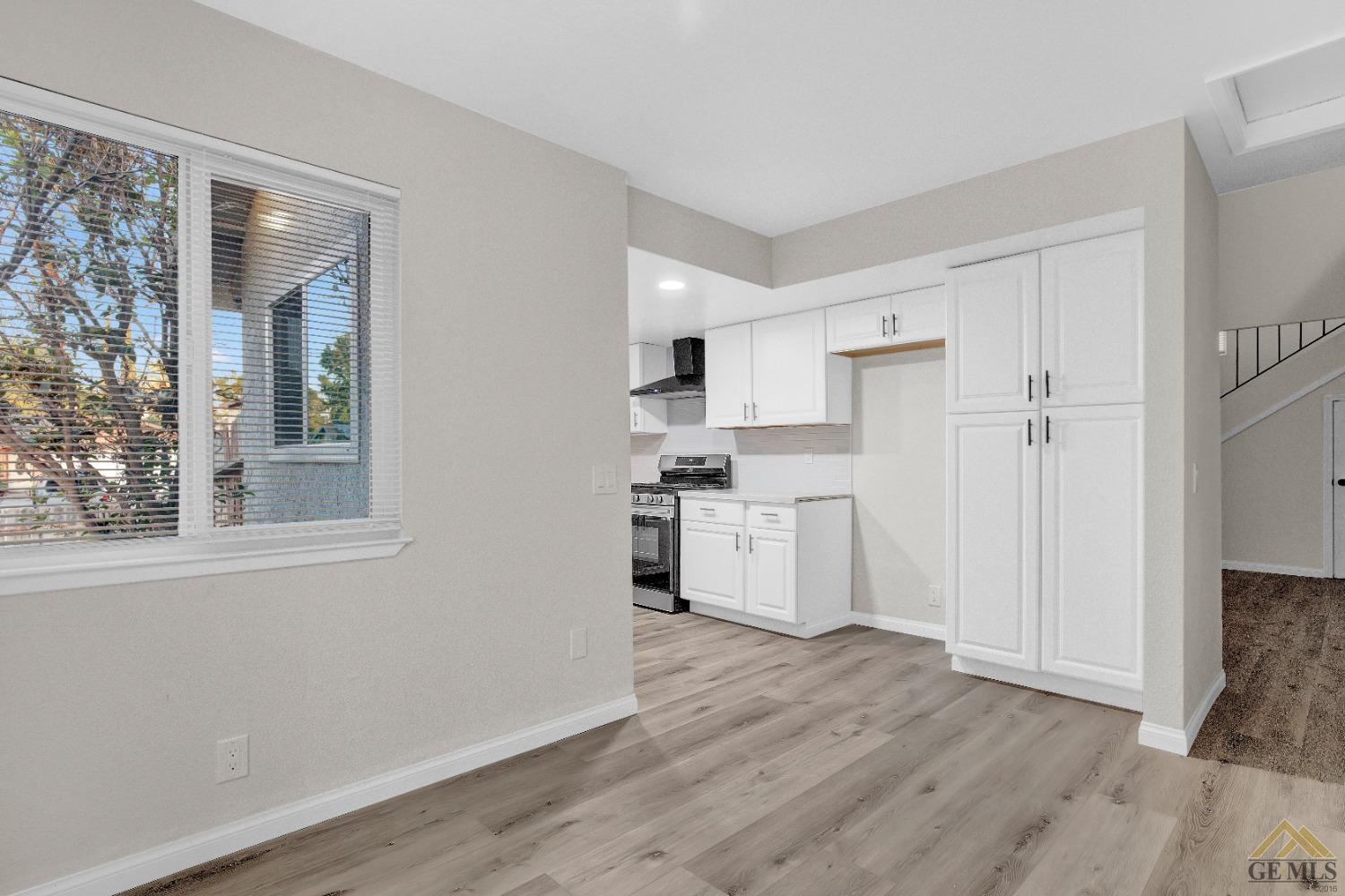 Undisclosed Address Bakersfield, CA 93304 - Photo 7 of 32 a kitchen with wooden floors and white cabinets