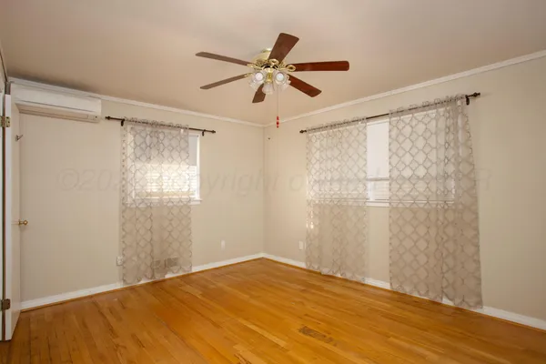a view of empty room with wooden floor and fan