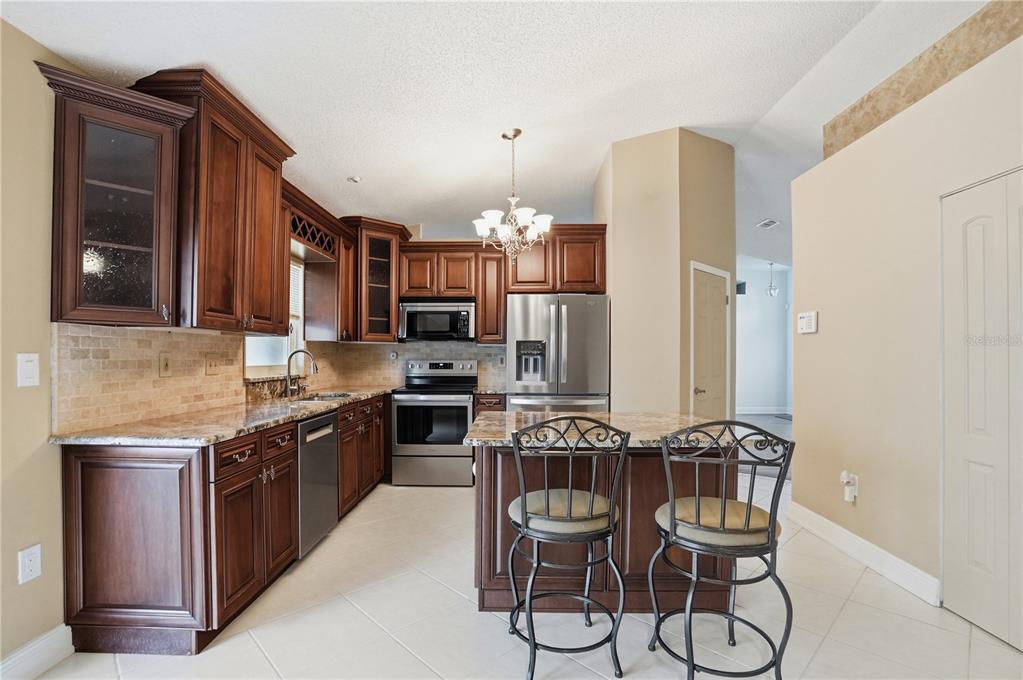 5277 Deltona Boulevard Spring Hill, FL 34606 - Photo 15 of 74 a kitchen with granite countertop stainless steel appliances a sink stove and cabinets