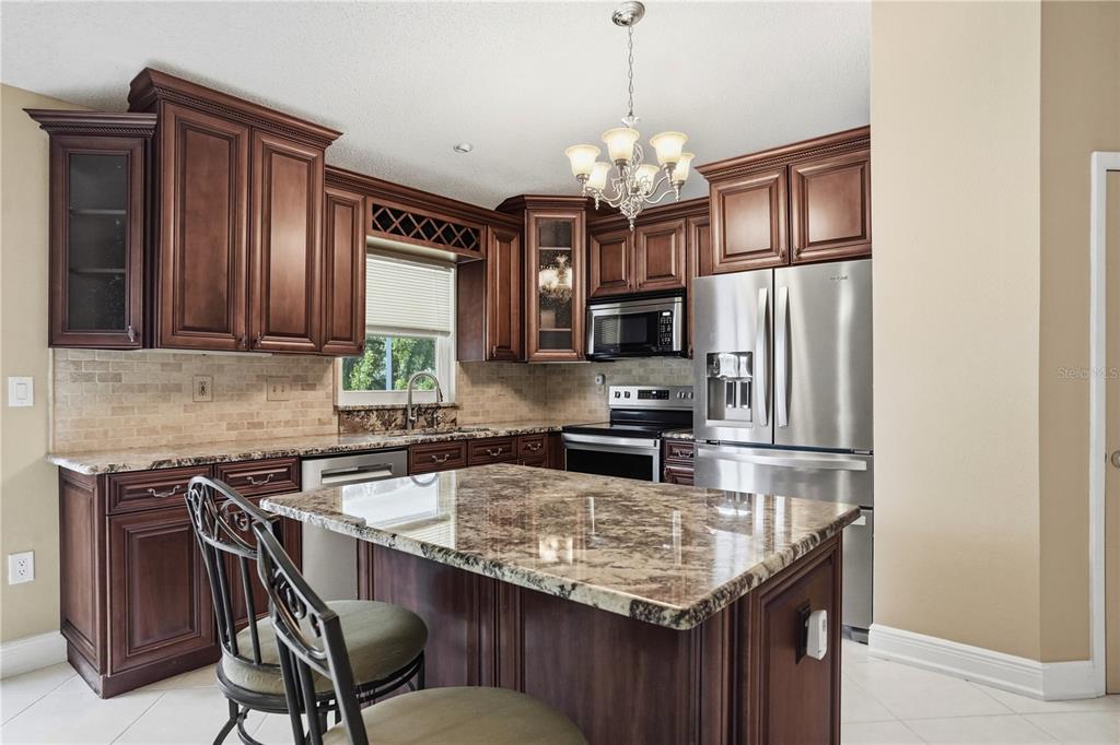 5277 Deltona Boulevard Spring Hill, FL 34606 - Photo 16 of 74 a kitchen with stainless steel appliances granite countertop a sink refrigerator stove and microwave