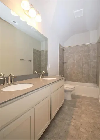 a bathroom with a double vanity sink a toilet and a bathtub