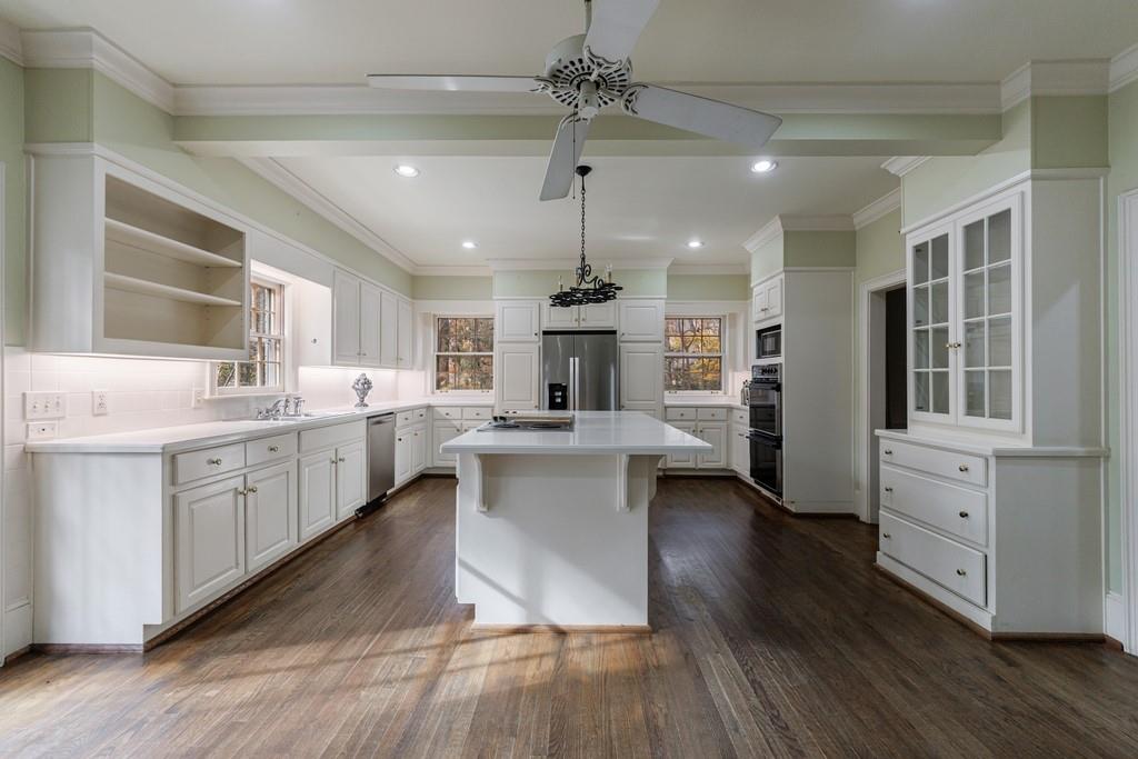 3990 Randall Mill Road Northwest Atlanta, GA 30327 - Photo 34 of 65 a large kitchen with kitchen island a stove a sink dishwasher a dining table and chairs with wooden floor