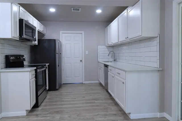 a kitchen with stainless steel appliances granite countertop a refrigerator a stove and a sink