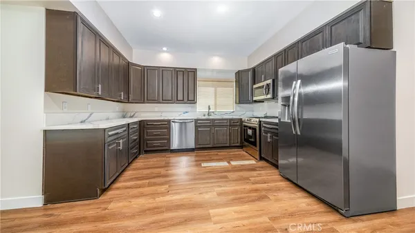 a kitchen with stainless steel appliances granite countertop a refrigerator a sink dishwasher a oven with wooden cabinets and floor