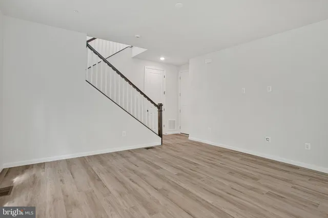 a view of an empty room with wooden floor and stairs