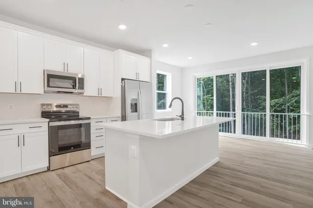 a kitchen with stainless steel appliances a stove a sink a refrigerator a window and white cabinets