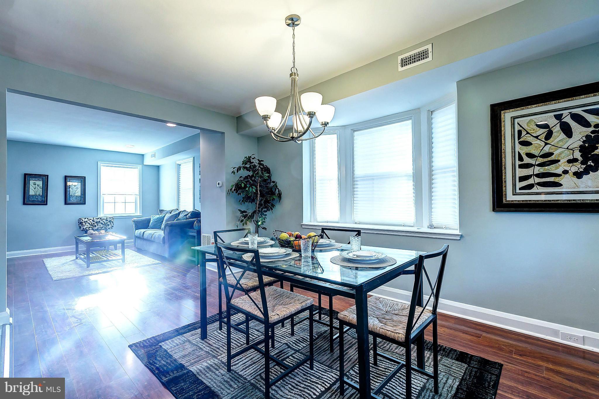 968 North Hill Road Baltimore, MD 21218 - Photo 7 of 29 a dining room with wooden floor a chandelier a wooden table and chairs