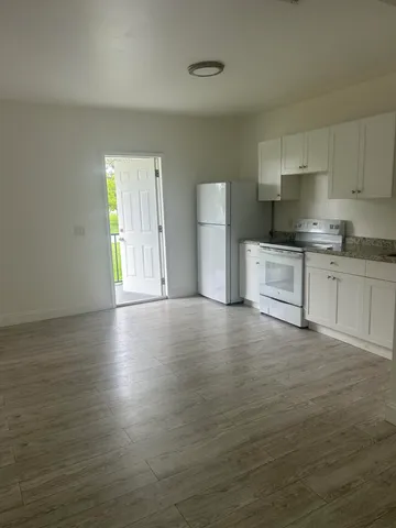 a kitchen with stainless steel appliances granite countertop a stove a sink and white cabinets with wooden floor