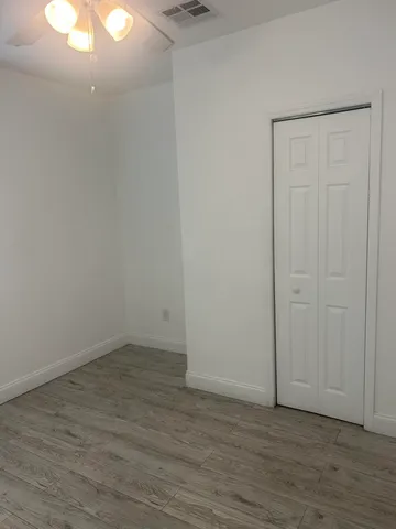 a view of an empty room with wooden floor and closet