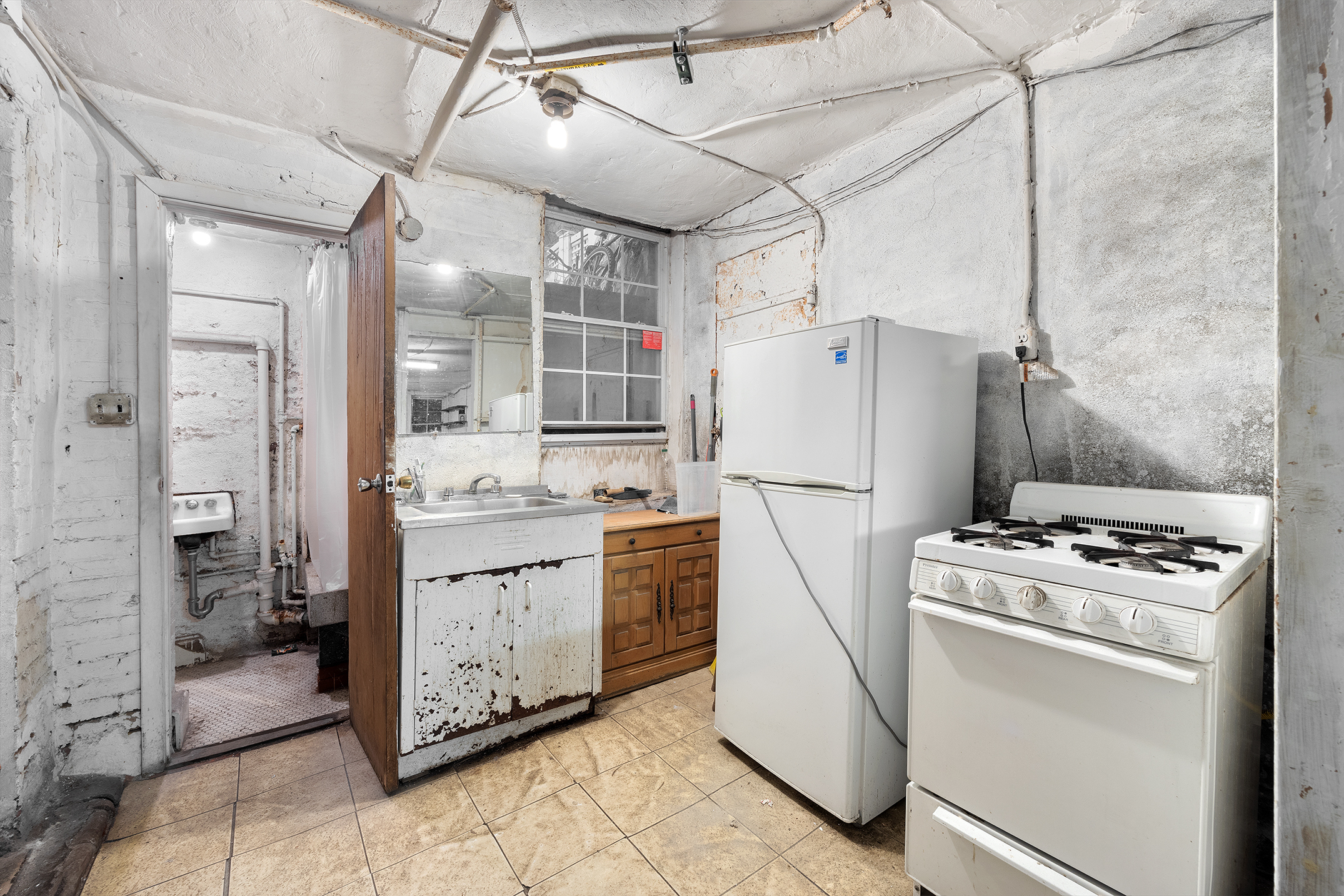 195 Prince Street, Unit 1LL Manhattan, NY 10012 - Photo 4 of 7 a kitchen with cabinets a refrigerator and a stove