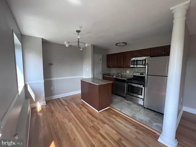 a kitchen with granite countertop a refrigerator and a stove top oven