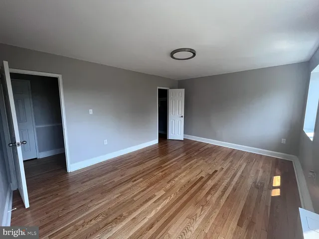an empty room with wooden floor and entrance