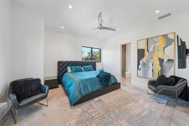 a spacious bedroom with a bed a couch and a large window