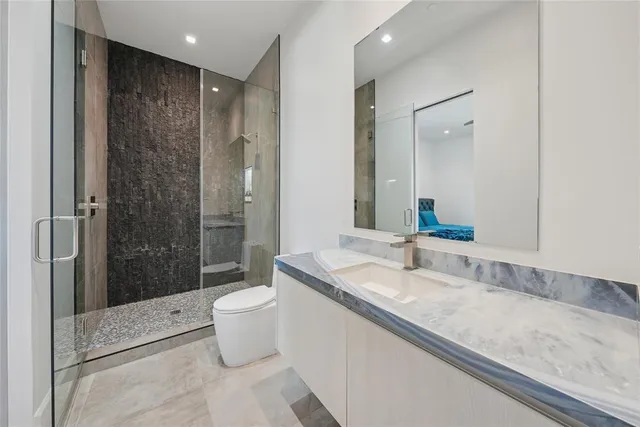 a bathroom with a granite countertop sink a toilet a mirror and shower