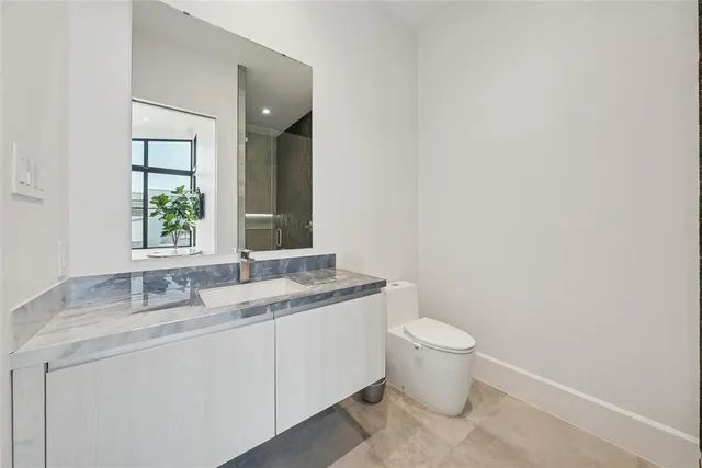 a bathroom with a granite countertop toilet a sink and a mirror