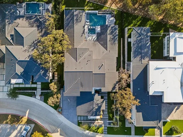 an aerial view of a house with swimming pool and large trees