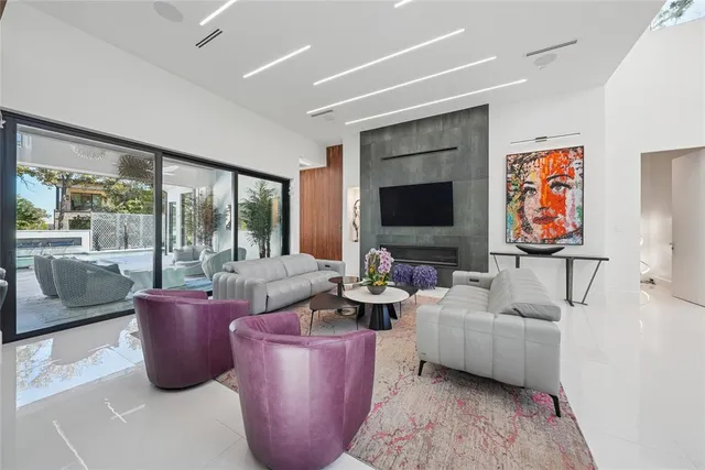 a living room with furniture a flat screen tv and a floor to ceiling window