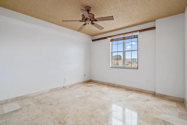 an empty room with windows and ceiling fan