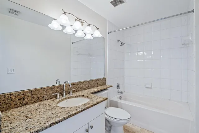 a bathroom with a granite countertop sink a toilet and bathtub