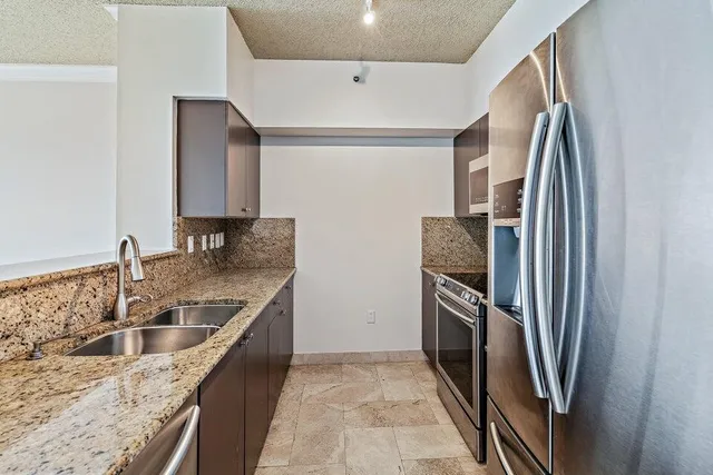 a kitchen with stainless steel appliances granite countertop a refrigerator and a sink