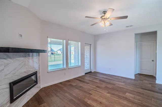 a view of an empty room with wooden floor and a kitchen