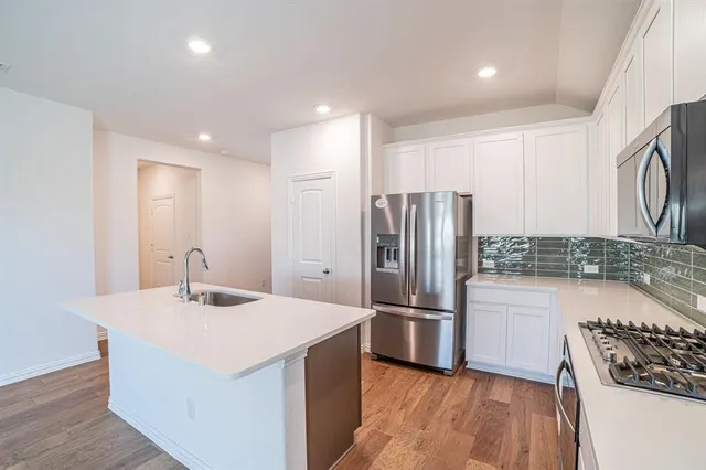 a kitchen with stainless steel appliances granite countertop a refrigerator stove a sink and dishwasher with wooden floor