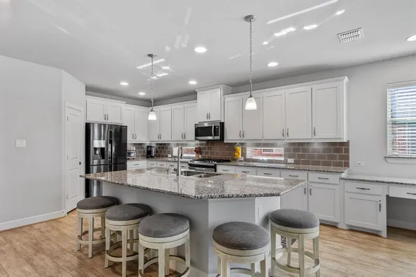 a kitchen with a dining table chairs stainless steel appliances and cabinets