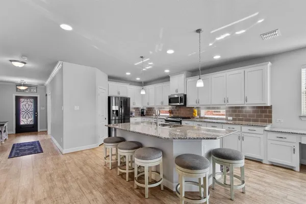 a kitchen with stainless steel appliances a dining table chairs and a refrigerator