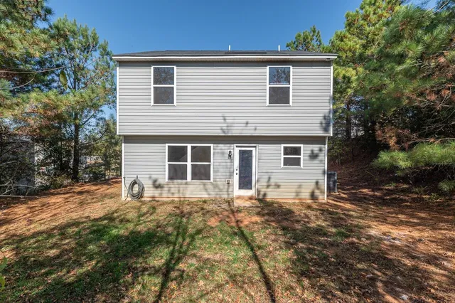 a front view of house with yard and trees in the background