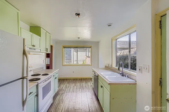a kitchen with a refrigerator a stove a sink and wooden floor
