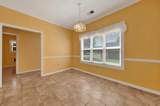 a view of an empty room with chandelier fan and fire place