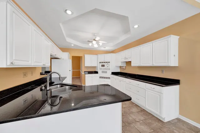 a kitchen with granite countertop a sink a counter top space appliances and cabinets
