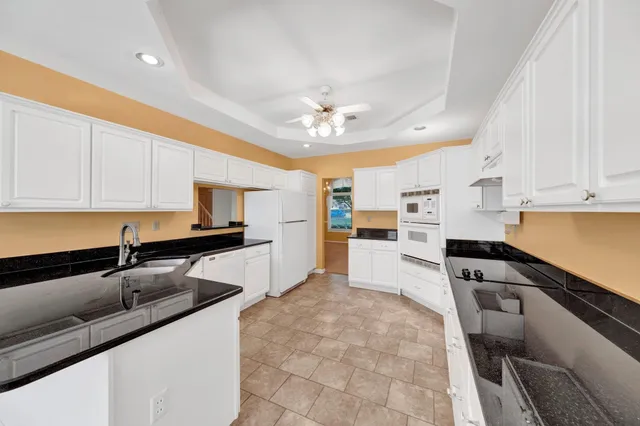 a kitchen with granite countertop white cabinets and white appliances