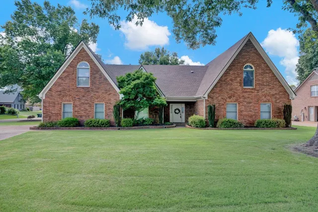 a front view of a house with a yard and trees