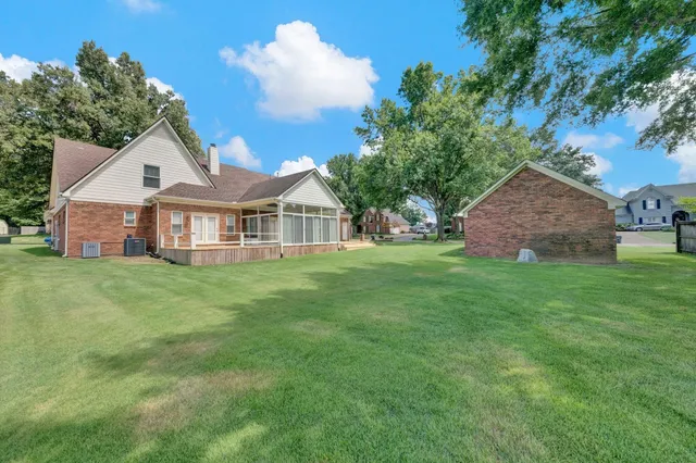 a view of a house with a yard and large tree