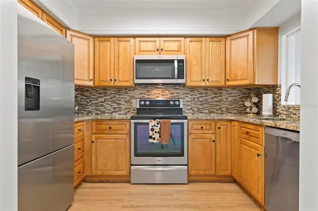 a kitchen with stainless steel appliances granite countertop a stove a sink and a microwave