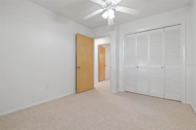 an empty room with a chandelier fan and closet area