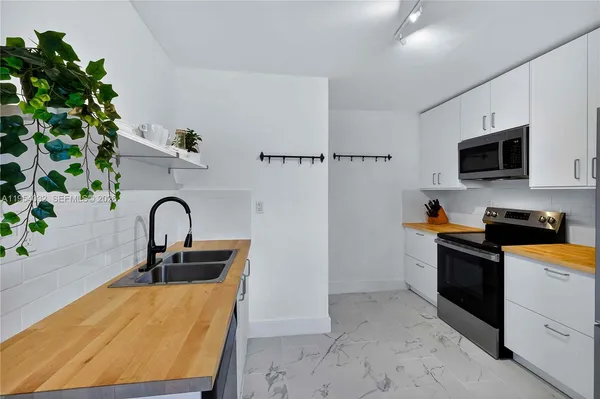 a kitchen with stainless steel appliances a sink a stove top oven a counter space and cabinets