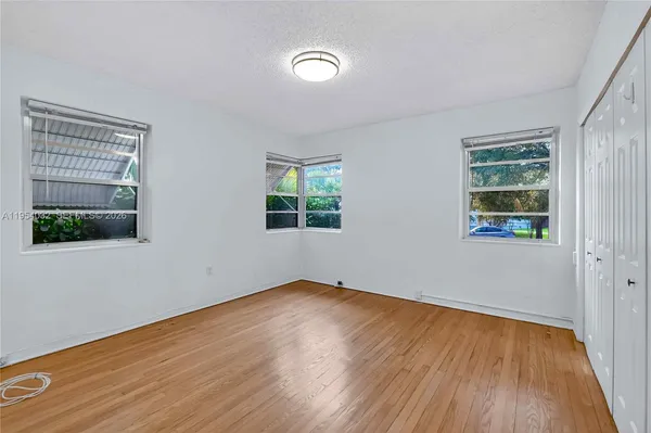 a view of empty room with wooden floor and fan