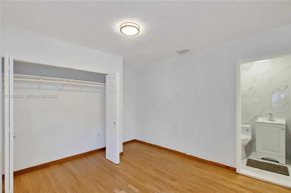 a view of an empty room with wooden floor and a fireplace