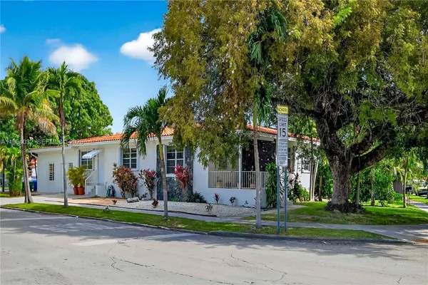 front view of house with a yard and large trees