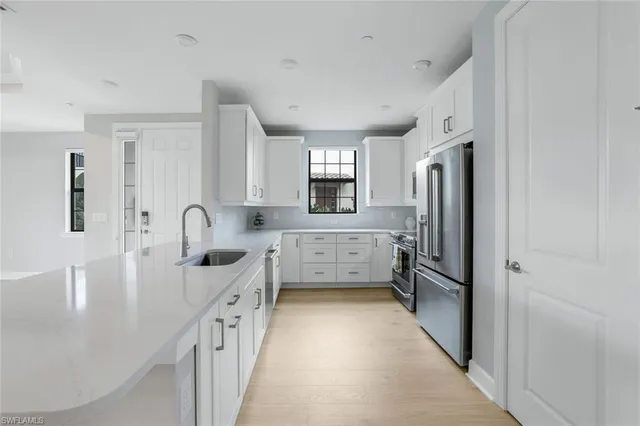 a kitchen with stainless steel appliances a refrigerator sink and white cabinets