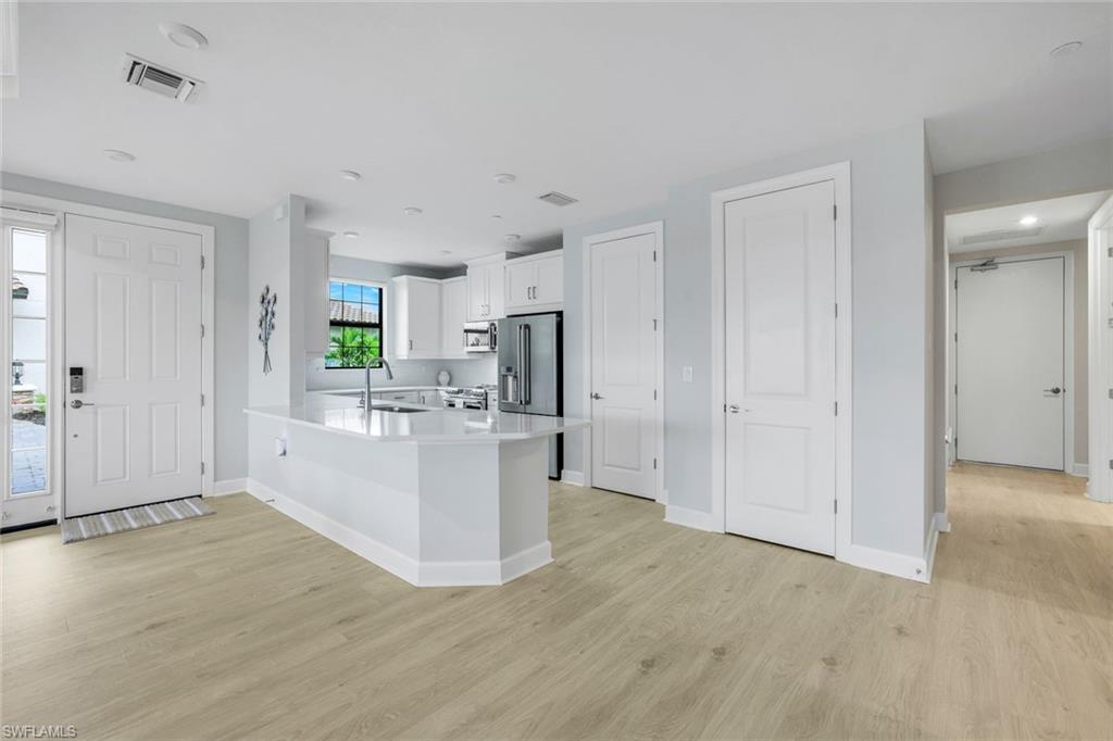 15336 Lucerna Street, Unit 104 Naples, FL 34114 - Photo 5 of 17 a view of kitchen with refrigerator stove microwave and cabinets
