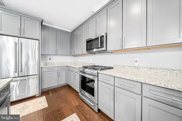 a kitchen with granite countertop a stove a sink and a microwave