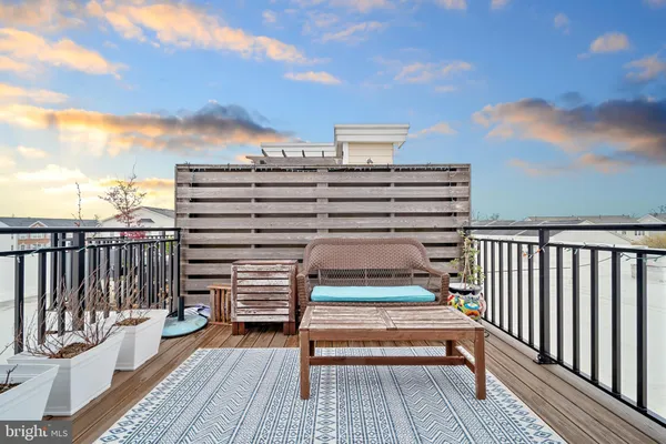 a balcony of a house with wooden floor outdoor seating and yard